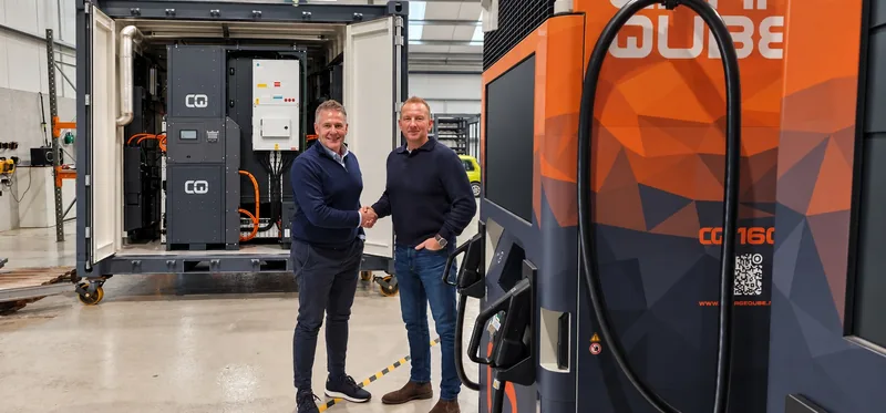 Simon Tate and Mike Ellenthorpe shaking hands alongside ChargeQube charging technology at Fellten’s facility